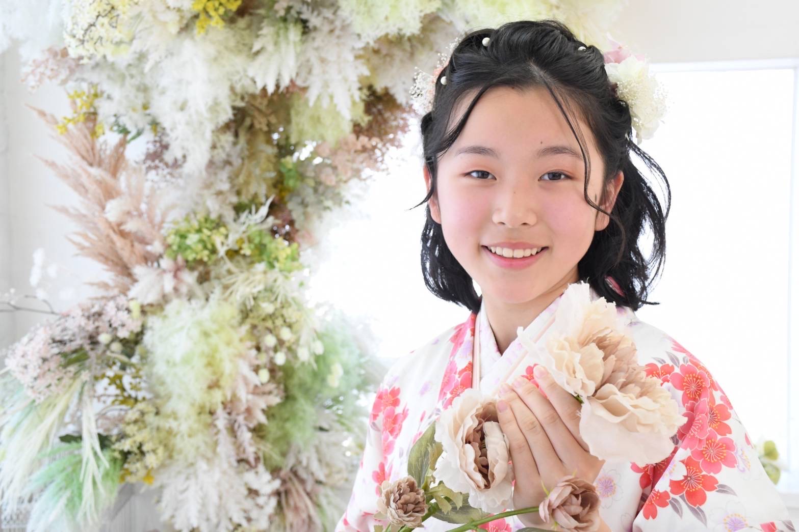 花を持つ着物姿の女の子の記念写真
