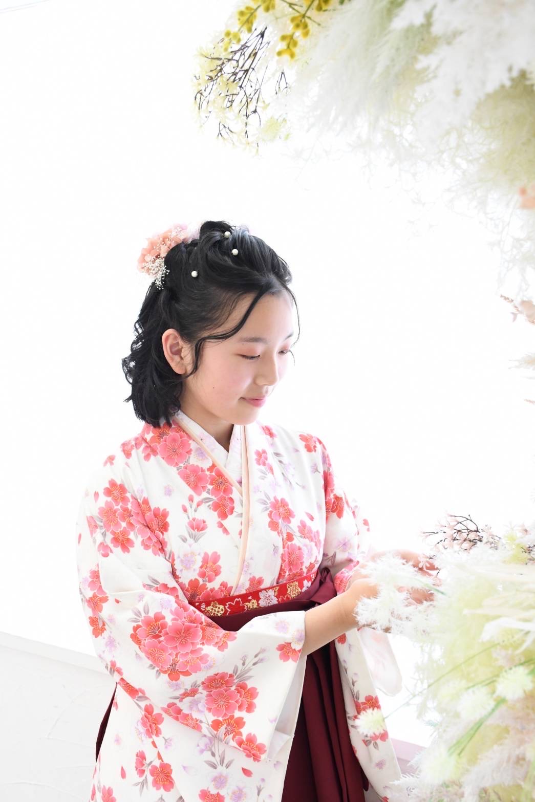花の前に立つ桃色の着物と袴姿の記念写真
